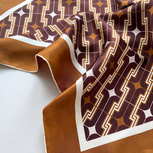 a 70s style printed silk scarf with hand-rolled edges in burgundy and yellowish brown tone