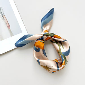 a silk bandana scarf featuring lily and butterfly print, knotted as a head scarf