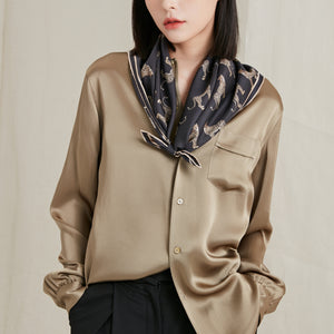a women in khaki brown shirt layering with a black base silk scarf featuring leopard print 