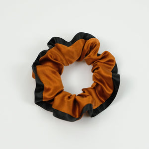 a burnt orange silk scrunchie with black edge