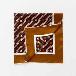 65x65cm brown silk scarf with a geometric pattern and hand-rolled edges, featuring a contrasting border. Retro-inspired unisex accessory, perfect for versatile styling around the neck, hair, or as an accent piece.