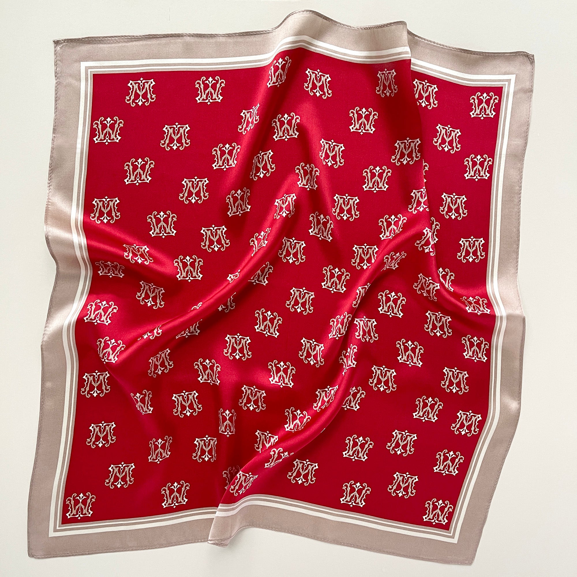 a red small silk scarf with beige edge featuring crown print