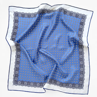 a cerulean blue square silk scarf with white base and navy blue hand-rolled hems, featuring boho style print