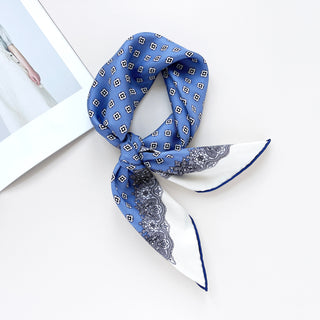 a cerulean blue square silk scarf with white base and navy blue hand-rolled hems, featuring boho style print, knotted as a neckerchief