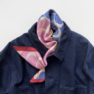 a luxury square silk scarf in lilac oink, blue, orange and yellow featuring burgundy hand-rolled edges and classic print, paired with a unisex denim jacket