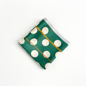 a jade green silk scarf bandana featuring light beige polka dot print and mustard yellow line near the edge, folded as a small square