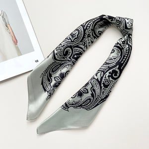 a pale pea green silk scarf with black boho style print, knotted as a necktie or headband
