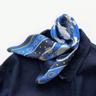 a bright blue men's silk scarf featuring classic horse riding and paisley prints with navy blue edge, paired with a men's denim top