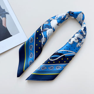 a bright blue men's silk scarf featuring classic horse riding and paisley prints with navy blue edge, tied as a necktie