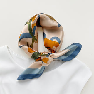 a small silk scarf in sky blue and orange featuring lily and butterfly prints knotted as a classic neck scarf