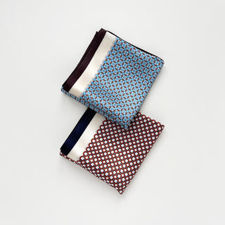 two silk scarves with featuring circle print in red and sky blue, folded as squares