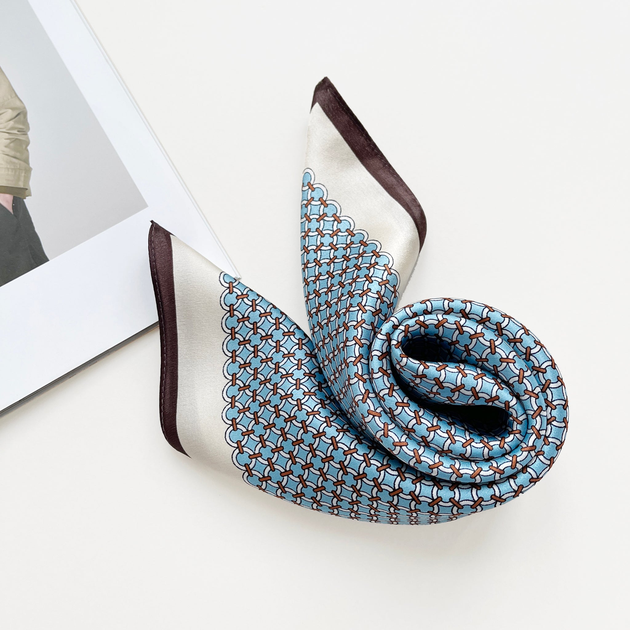 a small square silk scarf with brown edge featuring sky blue circle print