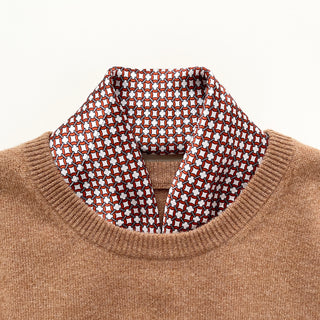 a silk scarf with navy blue edge featuring red circle print, tucked in a camel men's sweater