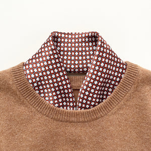 a silk scarf with navy blue edge featuring red circle print, tucked in a camel men's sweater