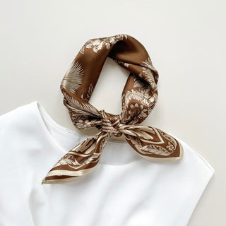 a bronze silk bandana scarf featuring beige botanic leaf print, knotted as a classic neckerchief 