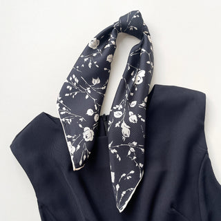 a black and white rose print silk scarf with handmade edges, knotted as a ponytail, paired with a black dress