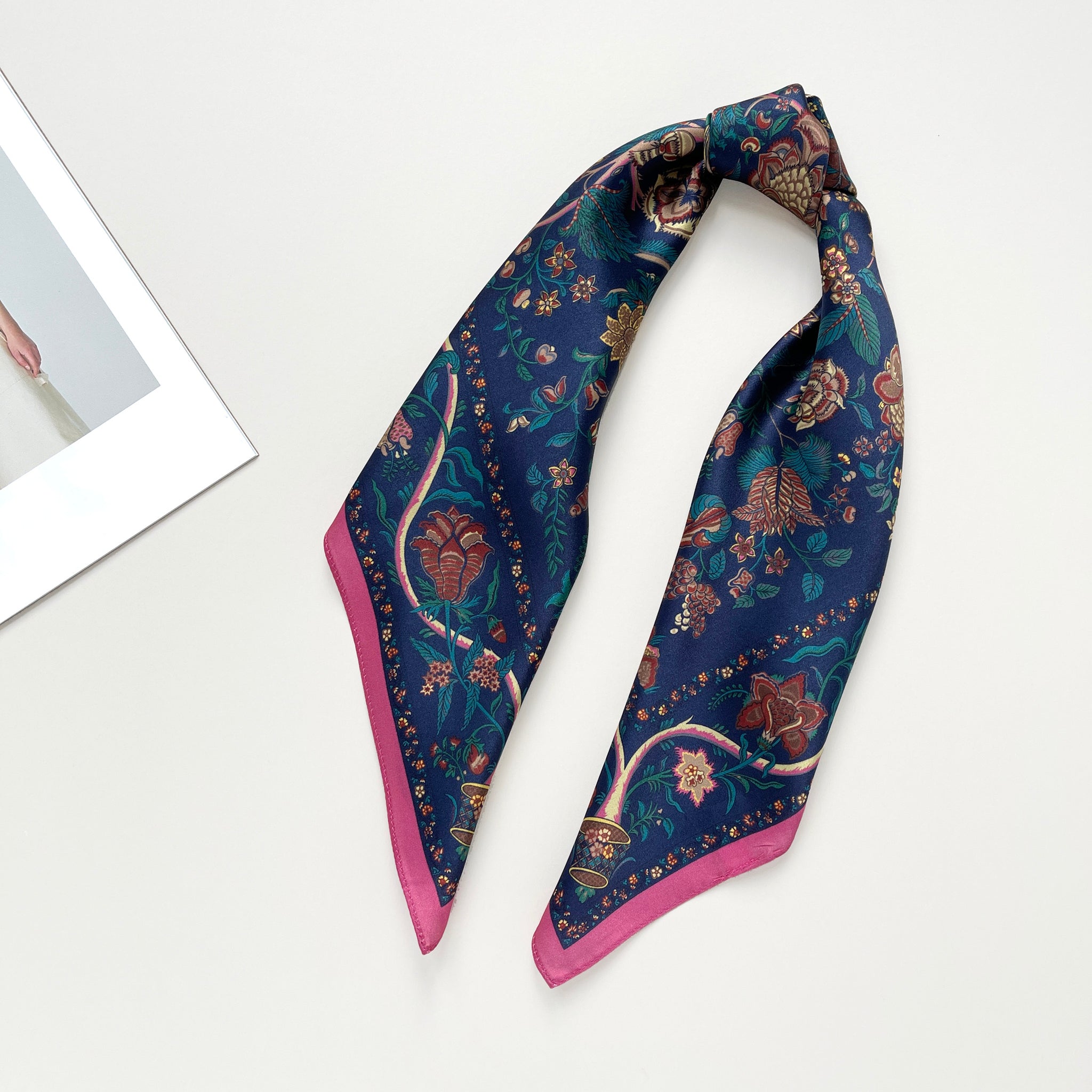 a blue vintage inspired floral silk scarf with magenta edge knotted as ponytail
