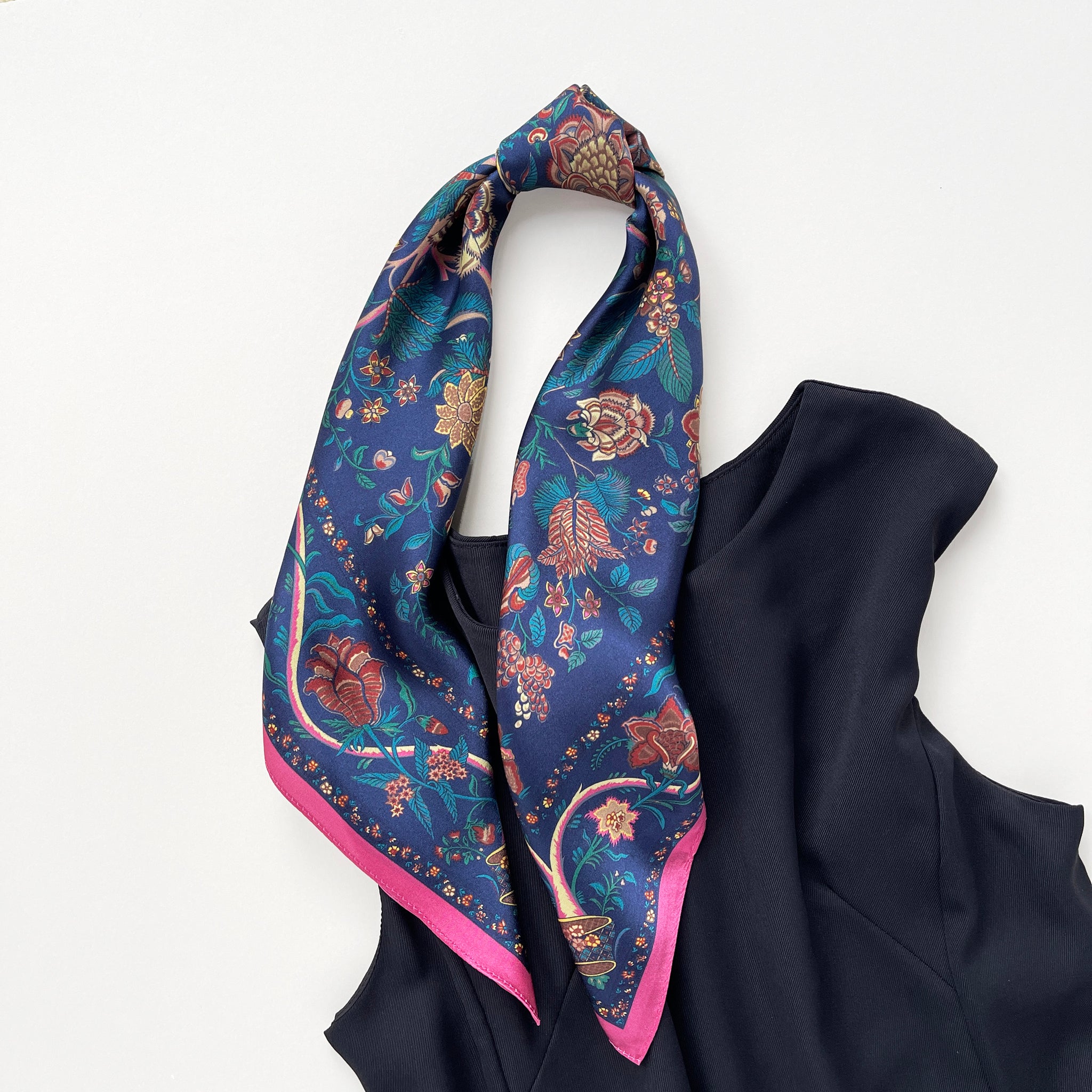 a blue vintage inspired floral silk scarf with magenta edge knotted as a ponytail, paired with a black sleeveless dress