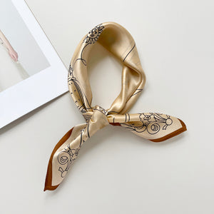 a timeless pale apricot silk bandana scarf featuring black print with brown edge, knotted as a classic neckerchief 
