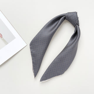 a classic silk scarf neckerchief featuring black and white checks and navy blue polka dots with white hand-rolled hems, knotted as a ponytail 