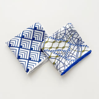 Unisex silk bandana with a white base and blue geometric pattern, featuring hand-rolled hems for an elegant finish. Versatile accessory for men and women, perfect for wearing around the neck or in the hair.