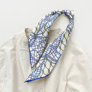 Unisex silk bandana with a white base and blue geometric pattern, featuring hand-rolled hems for an elegant finish. Versatile accessory for men and women, perfect for wearing around the neck or in the hair.