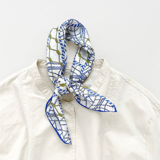 Unisex silk bandana with a white base and blue geometric pattern, featuring hand-rolled hems for an elegant finish. Versatile accessory for men and women, perfect for wearing around the neck or in the hair.