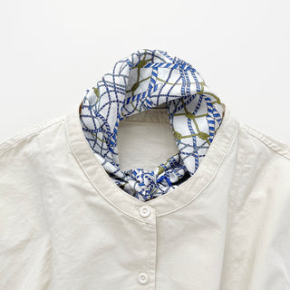 Unisex silk bandana with a white base and blue geometric pattern, featuring hand-rolled hems for an elegant finish. Versatile accessory for men and women, perfect for wearing around the neck or in the hair.