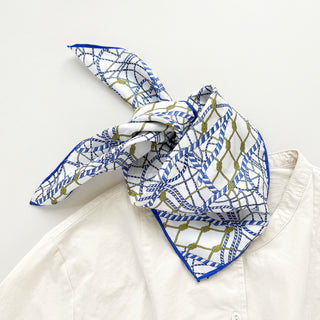 Unisex silk bandana with a white base and blue geometric pattern, featuring hand-rolled hems for an elegant finish. Versatile accessory for men and women, perfect for wearing around the neck or in the hair.