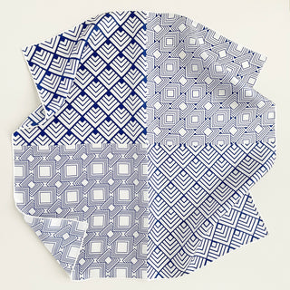 Unisex silk bandana with a white base and blue geometric pattern, featuring hand-rolled hems for an elegant finish. Versatile accessory for men and women, perfect for wearing around the neck or in the hair.