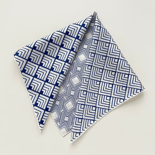 Unisex silk bandana with a white base and blue geometric pattern, featuring hand-rolled hems for an elegant finish. Versatile accessory for men and women, perfect for wearing around the neck or in the hair.