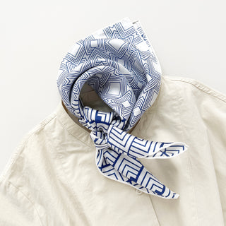 Unisex silk bandana with a white base and blue geometric pattern, featuring hand-rolled hems for an elegant finish. Versatile accessory for men and women, perfect for wearing around the neck or in the hair.