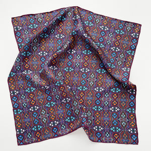 a small silk scarf bandana featuring an abstract intricate pattern in plum purple, blue and orange hues with hand-rolled hems 