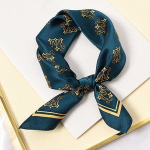an ocean blue small silk scarf featuring crown print, knotted as a neckerchief