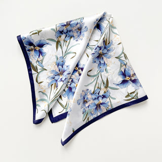 a silk bandana scarf featuring blue bell print with a white base and navy blue edges