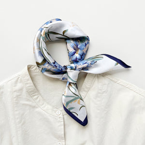 a silk bandana scarf featuring blue bell print knotted as a neckerchief, paired with a light beige women's turtle neck shirt