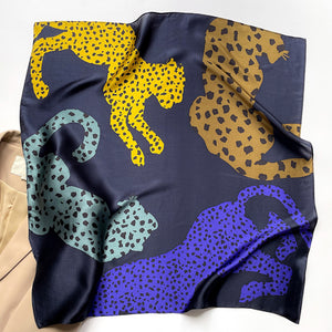 a leopard print square silk scarf in navy blue, indigo blue, yellow, black and bronze hues