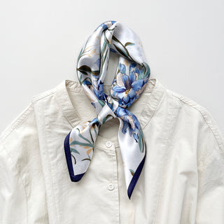 a silk bandana scarf featuring blue bell print knotted as a neckerchief, paired with a light beige women's turtle neck shirt