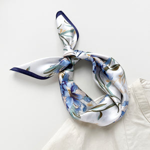 a silk bandana scarf featuring blue bell print knotted as a headband, paired with a light beige women's turtle neck shirt