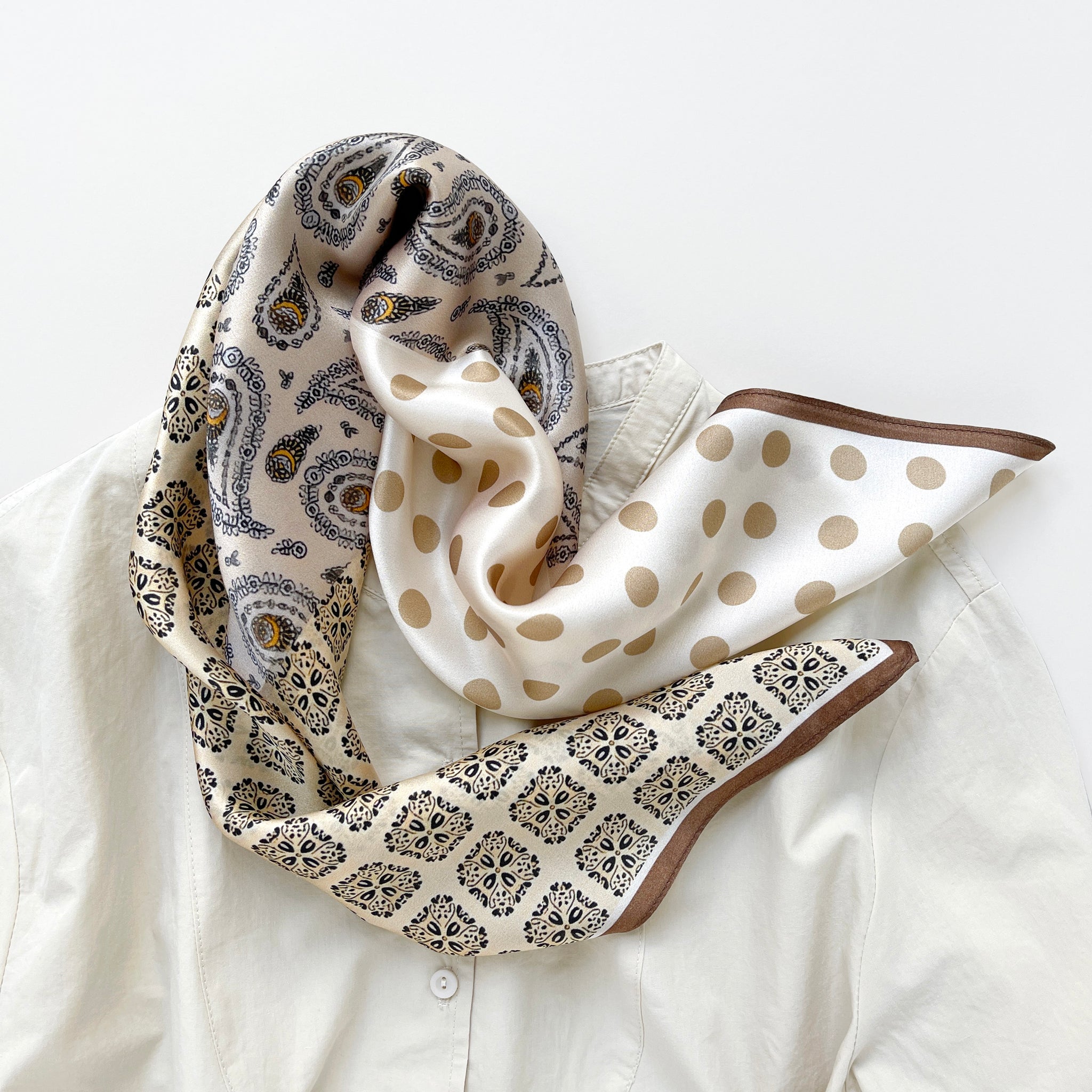 a beige and brown earth tones silk scarf featuring bohemian paisley and polka dot prints with brown edges paired with a beige women's turtle neck shirt