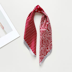 a vibrant red silk bandana scarf featuring paisley and polka dot pattern, knotted as a ponytail scarf