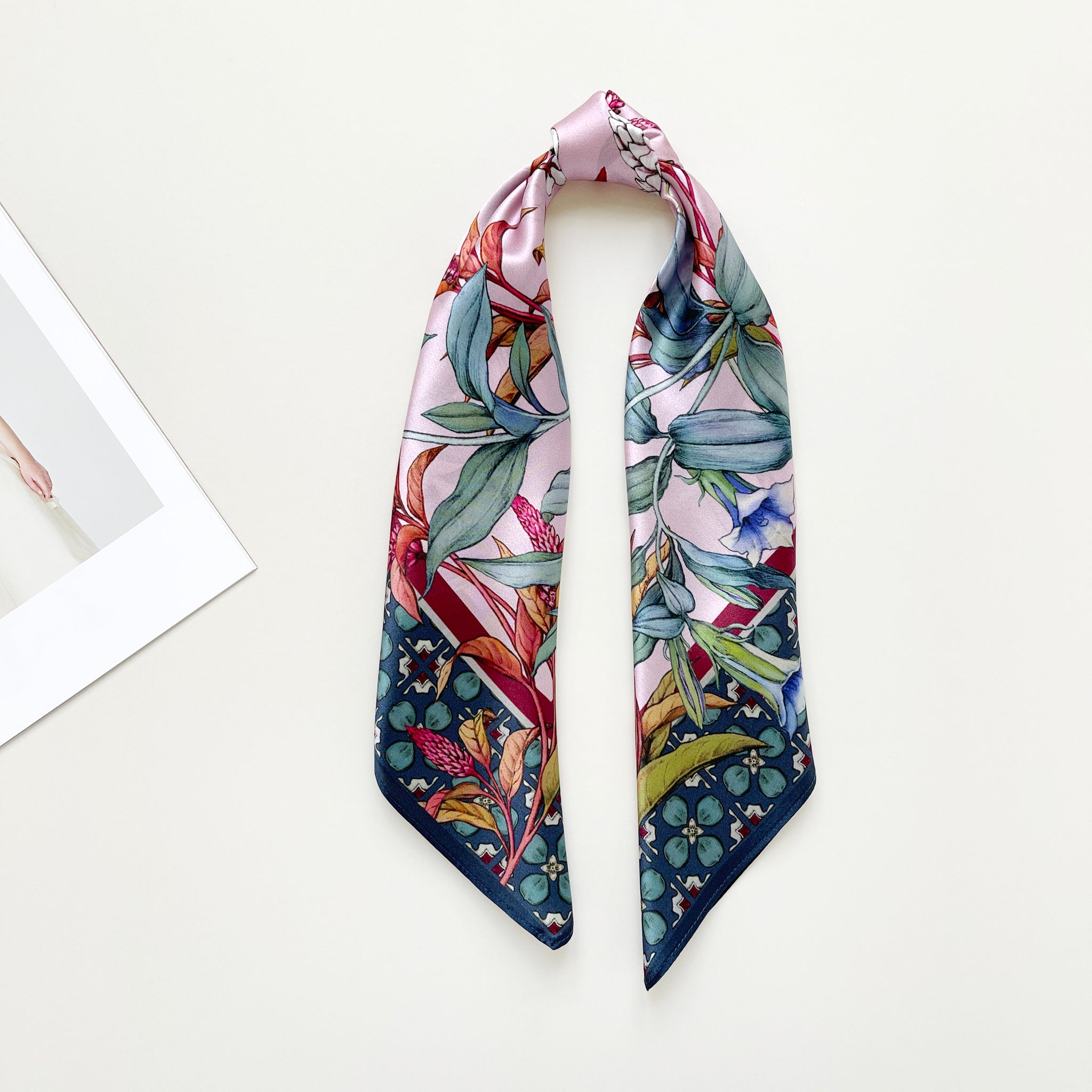 a pink base silk scarf featuring botanic floral print, tied as a ponytail scarf