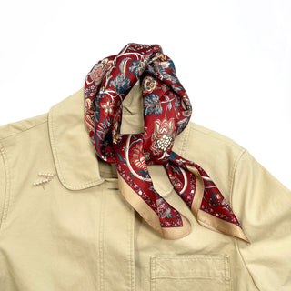 a red vintage inspired floral silk scarf with beige edge, tied as a neck scarf, paired with a beige coat