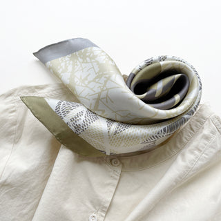 a forest leafy printed square silk scarf in sage green, grey and white tones with hand-rolled edges, paired with a light beige women's shirt