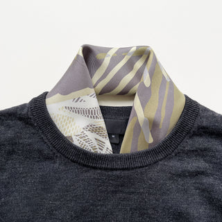 a forest leafy printed square silk scarf in sage green, grey and white tones with hand-rolled edges, paired with a men's dark grey sweater