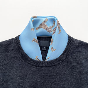 a sky blue base silk scarf featuring leopard print with hand-rolled edges, tucked in a men's dark grey sweater as a neck scarf