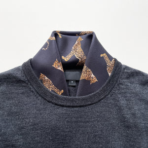 a black base silk scarf featuring leopard print with hand-rolled edges, tucked in a men's dark grey sweater as a neck scarf