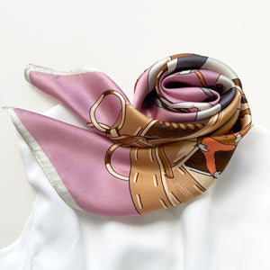 a pink silk square scarf featuring acrobatic dancers print in elegant pink and beige brown hues, paired with a white dress
