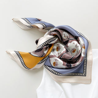 a women's silk scarf bandana featuring white rock roses print with cornflower blue and orange edges, knotted as a bandana bib, paired with a white dress