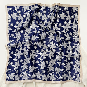 a deep blue silk bandana scarf featuring floral print with light beige edges